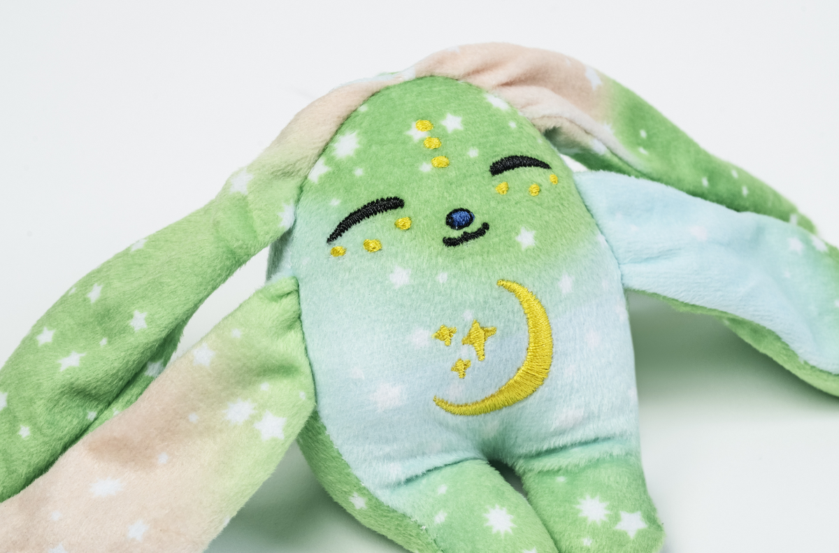 Clover Mini Wrist Hugger – Magnetic Sensory Plush, a green comfort rabbit with long ears, closed eyes, and an embroidered moon and stars on its chest, designed as a magnetic fidget toy.