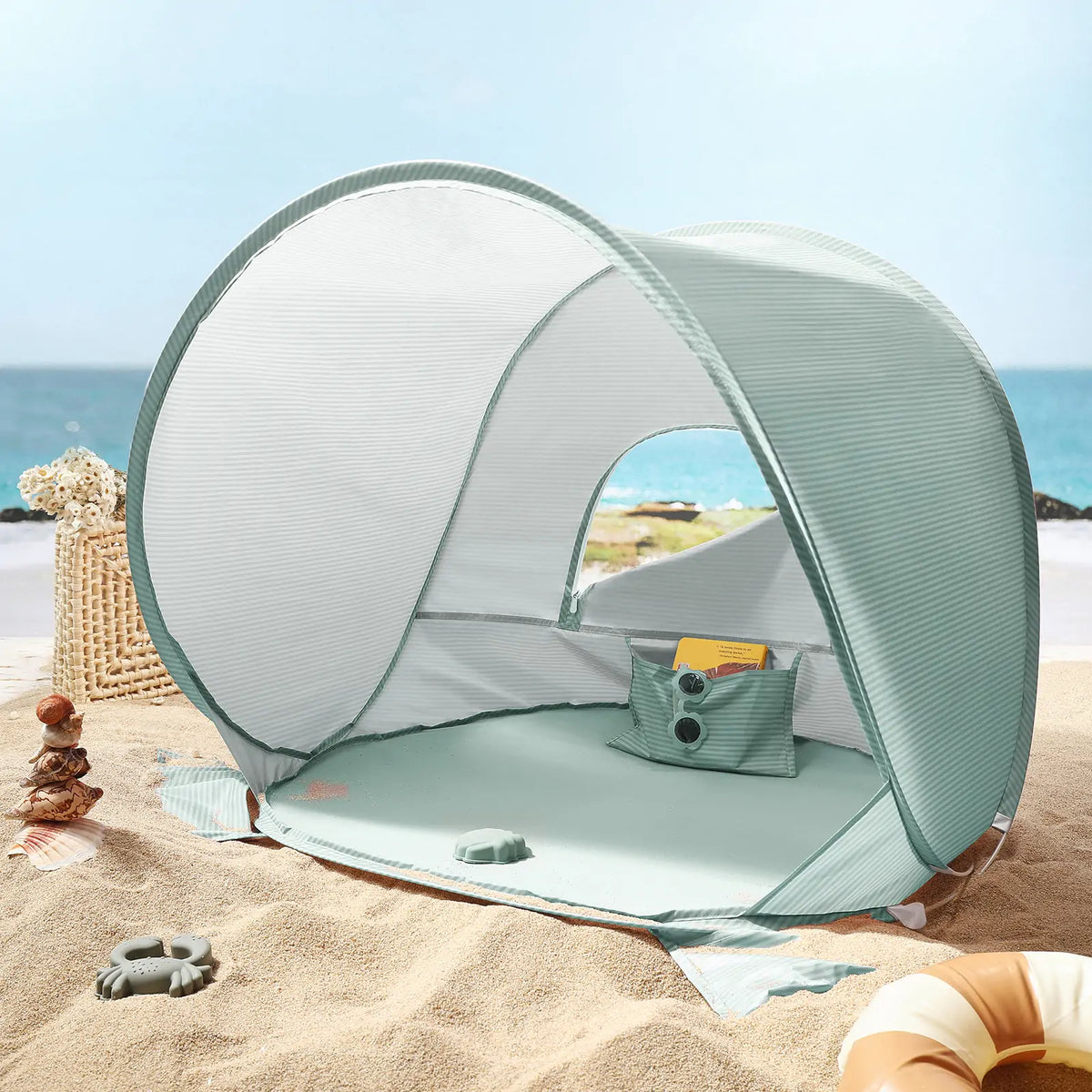 Sea blue Kids Beach Tent & Sand Toy Set on sand, with a scattered sand toy set nearby and the ocean in the background.