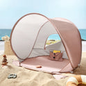 Blush pink Kids Beach Tent & Sand Toy Set with a mesh window and interior storage pocket, surrounded by a sand toy set on a beach.
