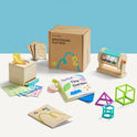 The Tiny Land® Montessori Toys for Newborns (4–6 Months) includes wooden toys, colorful fabrics, a rattle, stacking shapes, and booklets—thoughtfully organized to promote fine motor skills with the brown Montessori Play Box in the background.