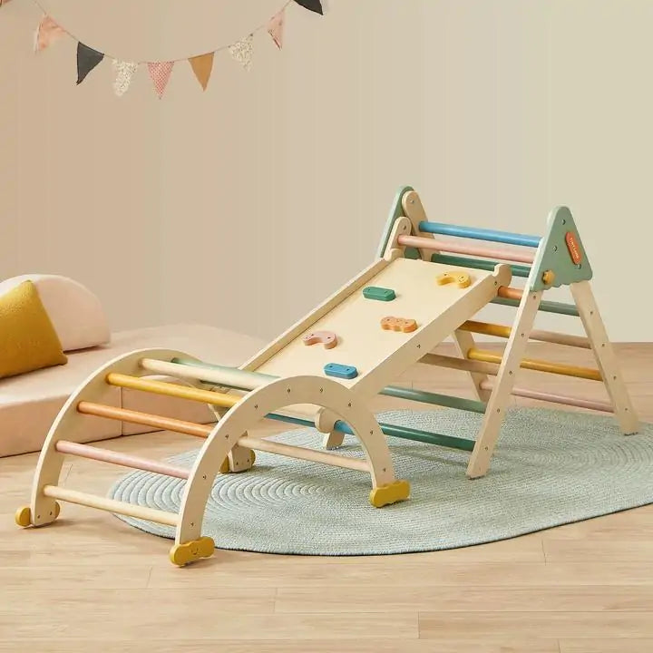 A 7-in-1 Montessori Pikler Triangle Set – Morandi with a triangle, arch, and reversible ramp in pastel colors arranged on a rug.