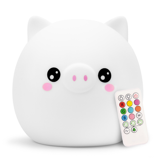 A white, soft silicone Percy the Pig Silicone Night Light next to a small remote control with multi-colored buttons for the color-changing light.