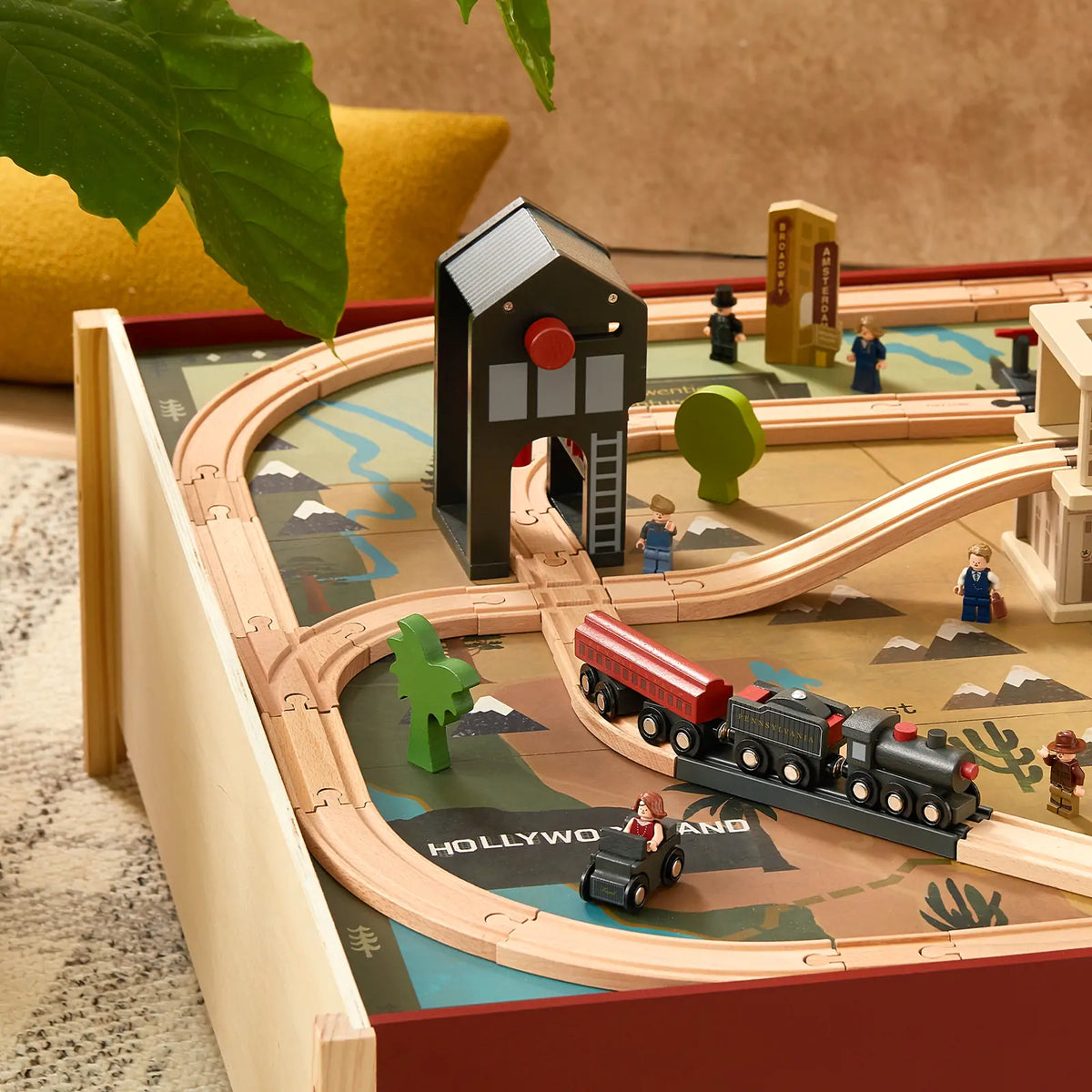 The 1920s Railway Wooden Train Table with Sounds features a locomotive, cars, figures, a shed, and tracks set upon a printed vintage city scene map.