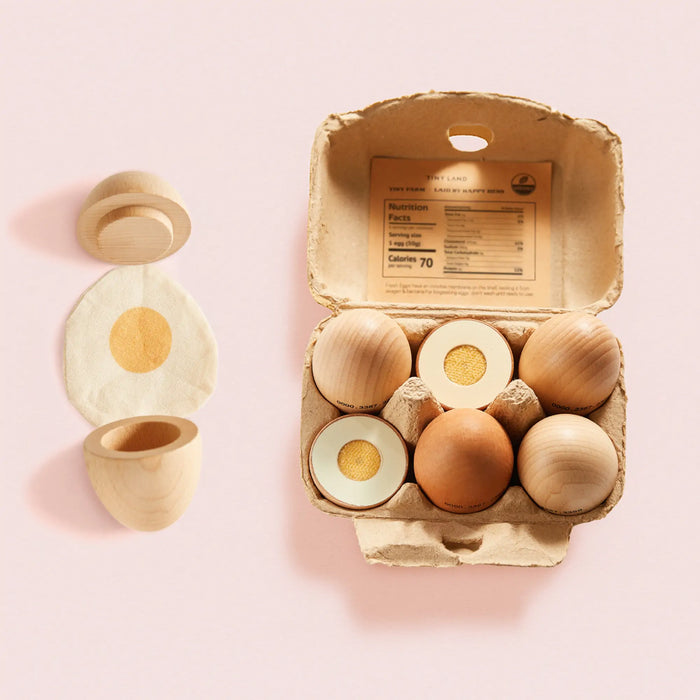 A Wooden Egg Breakfast Play Set (6 pc) featuring a wooden carton with five eggs, including one disassembled egg with a felt yolk placed beside it.