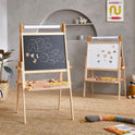 Two Tiny Land® Magnitales Easels for Kids stand in a cozy playroom: one has a chalkboard with “ABC IDE?” written on it, and the other is a magnetic art easel showing scattered letters. Toys and art supplies are neatly organized around the room.