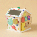 Montessori Cottage Activity Cube – Rainbow: a wooden house-shaped activity cube featuring colorful polka dots, a roof mirror, spinning discs, peek-a-boo doors, and sliders to develop fine motor skills.