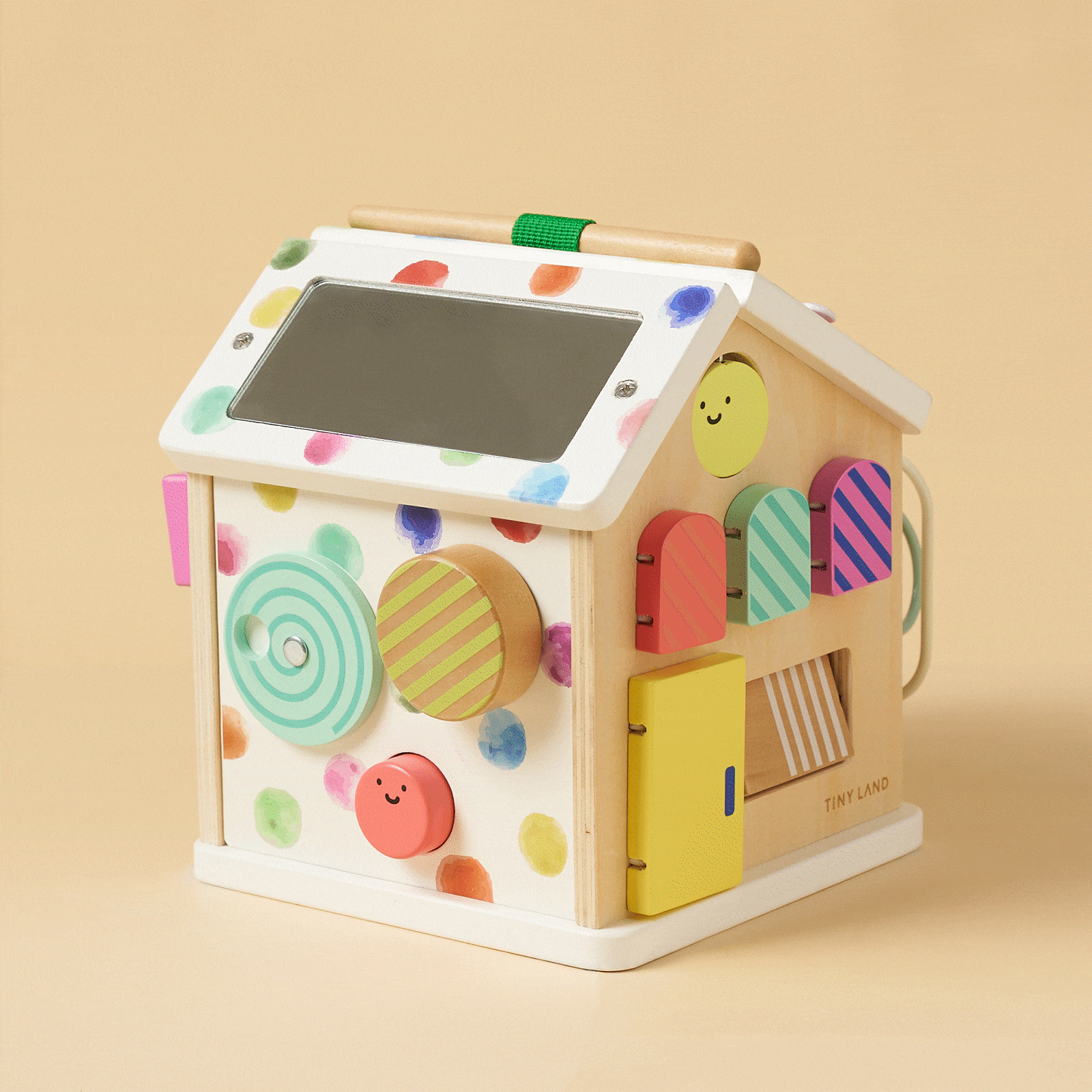 Montessori Cottage Activity Cube – Rainbow: a wooden house-shaped activity cube featuring colorful polka dots, a roof mirror, spinning discs, peek-a-boo doors, and sliders to develop fine motor skills.