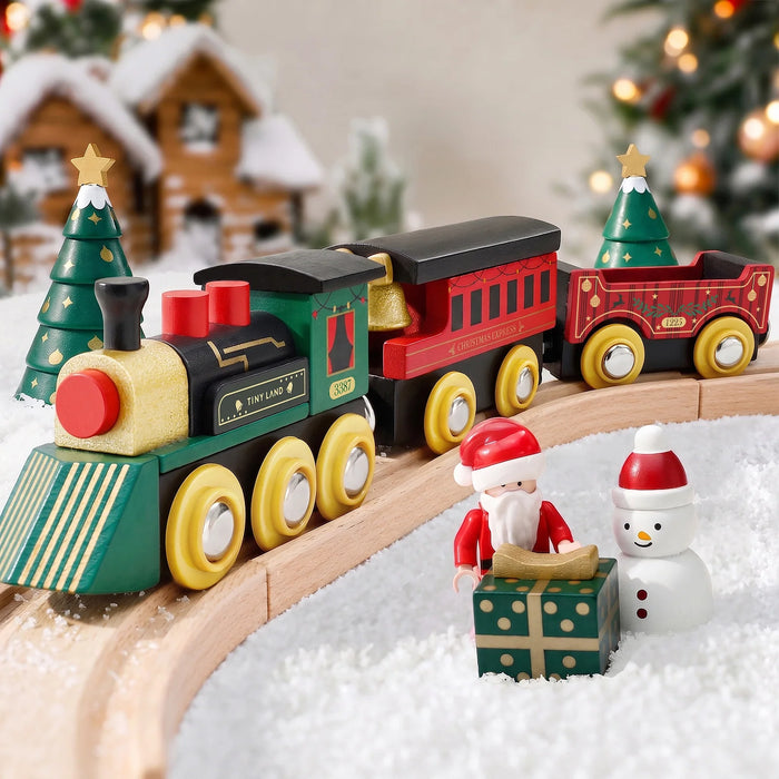 A Christmas Express Wooden Train Set with a festive engine and cars on a track, accompanied by a Santa Claus figurine, a snowman, and a wrapped gift on a bed of artificial snow.