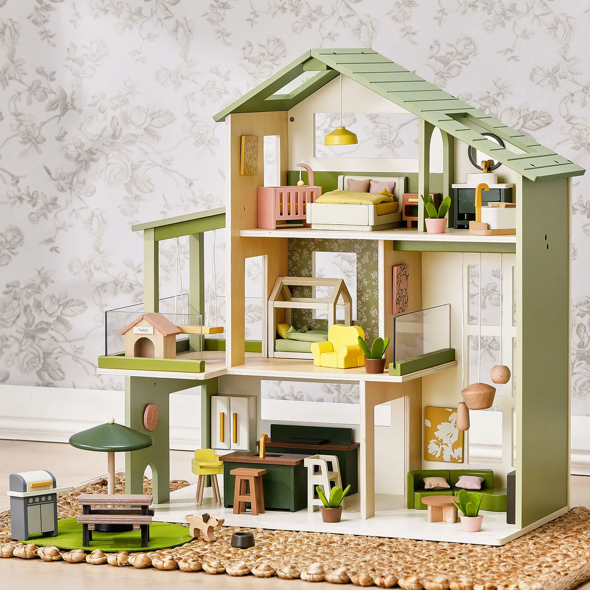 The Sweetwood Cottage Dollhouse (48-pc Furniture) is a three-story green and white wooden dollhouse featuring forty-eight 1:12 scale pieces, including a patio set, kitchen, living room, and bedroom.