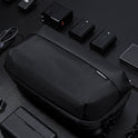 A Tech Pouch sits on a dark surface, neatly surrounded by camera batteries, chargers, cables, and electronic accessories.