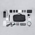 A neatly arranged flat lay features a Tech Pouch along with a smartphone, charging cables, adapters, memory cards, Apple Magic Mouse, digital pen, stylus, and other small gadgets on a light grey background.