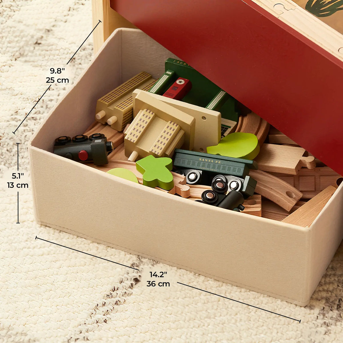 1920s Railway Wooden Train Table with Sounds storage bin filled with wooden toy train tracks, cars, and buildings for a vintage city scene, with dimensions labeled on the side.