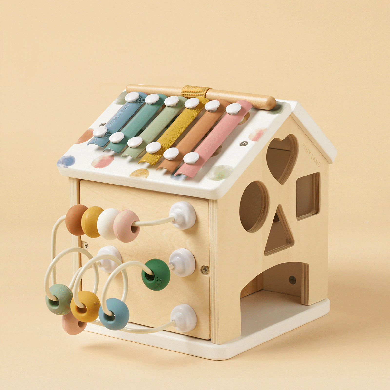 Montessori Cottage Activity Cube – Morandi, a wooden house-shaped toy featuring a xylophone roof, a side bead maze, and shape-sorting cutouts to support fine motor skills.