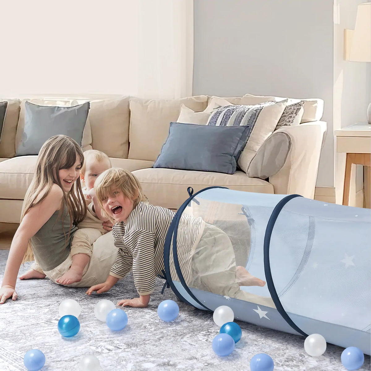 Three children play on a rug with a blue mesh play tunnel and scattered Ball Pit Balls (200 pc) – Soft Mixed Tones.