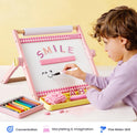 A child draws a smiley face on a 3-in-1 Adjustable Tabletop Art Easel that displays the word SMILE in magnetic letters.