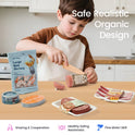 A child plays with a Pretend Meat & Seafood Play Pack, including a shrimp bag, a tuna can, a salmon fillet, a sausage, a steak, and bacon, while enjoying kitchen play on a table.
