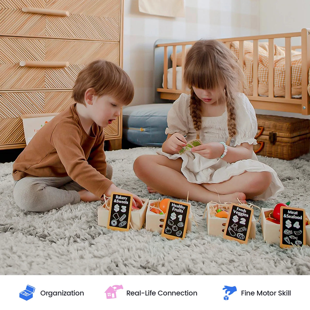 Two children sit on a rug playing with a Wooden Play Food Set & Storage Rack Bundle, where crates feature chalkboard-style signs indicating the category and price.