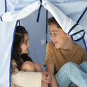 A young girl and boy sit inside a light blue Starry Indoor Play Tent for Toddlers patterned with white stars, looking at each other and smiling.