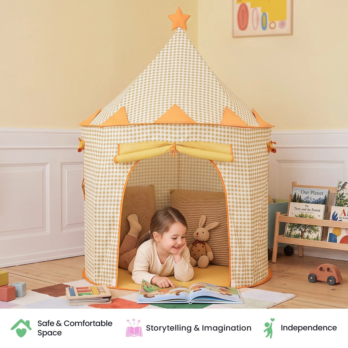 A child reads a book inside a beige and white checkered Starry Indoor Play Tent for Toddlers, accompanied by a stuffed rabbit and pillows.
