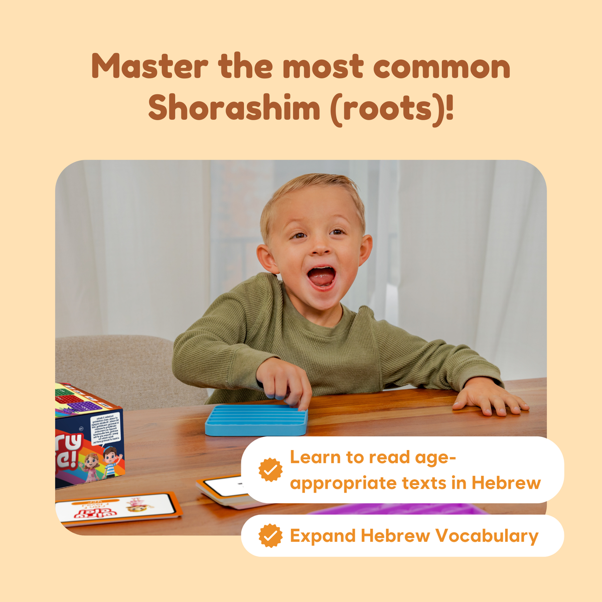 A young boy smiles with excitement while using the Shoresh Pop! Hebrew Roots Reading Game, featuring Hebrew word cards and a blue fidget game to practice Hebrew roots.