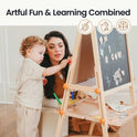 A woman and child play with the Tiny Land® Magnitales Easel for Kids, arranging magnetic letters on its height-adjustable chalkboard. “Artful Fun & Learning Combined” is displayed above, with art supplies on the easel’s convenient tray.