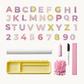 A 3-in-1 Adjustable Tabletop Art Easel with uppercase letters and numbers zero through one, a white paper roll, yellow storage tray, pink chalk, black marker, pink duster, and pink ruler.