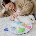 A woman in a tan sweater smiles while playing with a baby lying on a soft quilt, who is enjoying tummy time with Tiny Land® Montessori Toys for Newborns (0–3 Months).