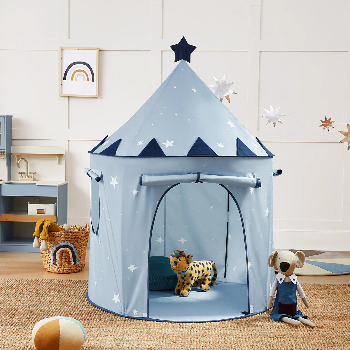 Starry Indoor Play Tent for Toddlers: a light blue clubhouse decorated with white stars, featuring a star-shaped topper and a doorway revealing a toy leopard inside.