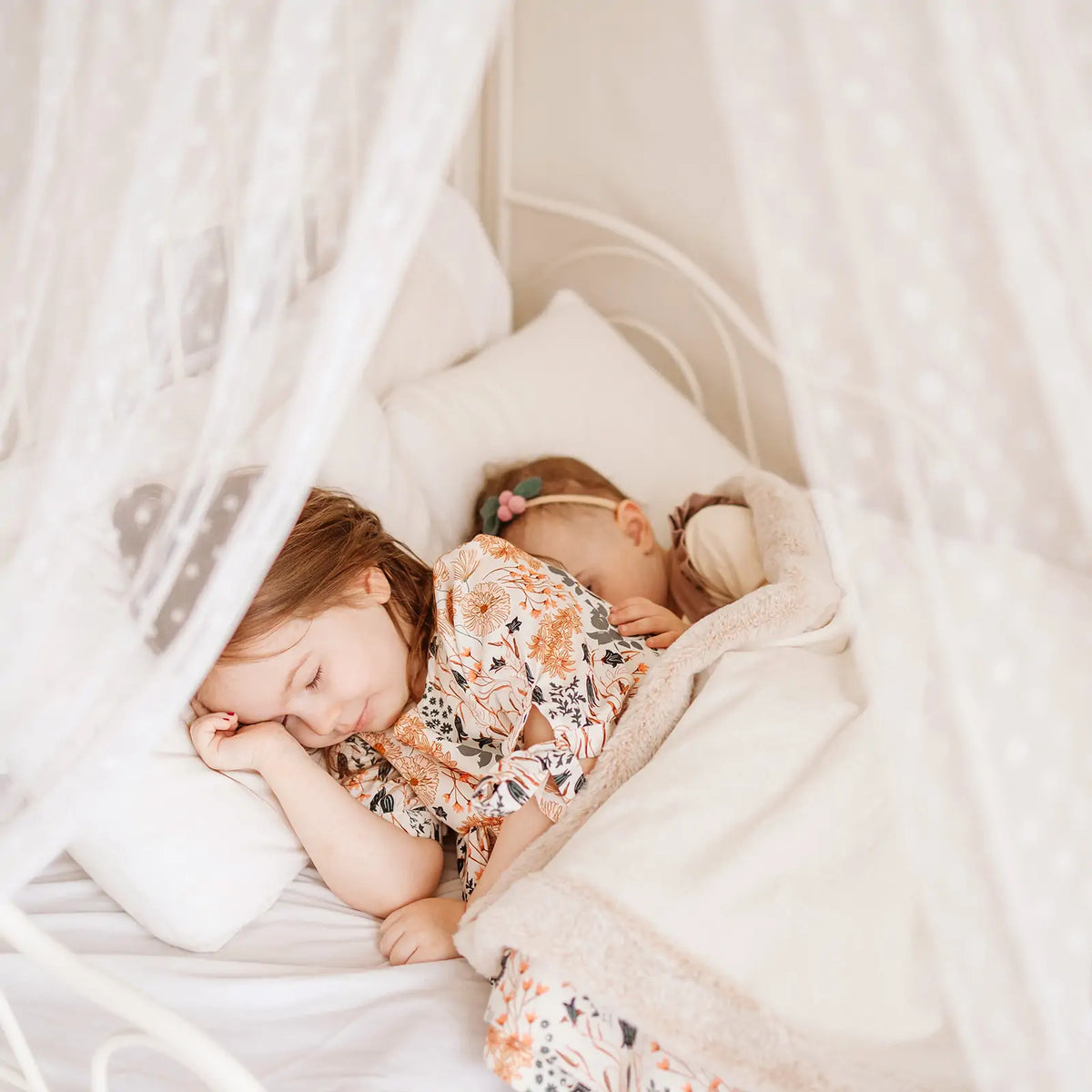 Two children sleeping inside a Large Cozy Cabin Play Tent with Star Lights, draped with white fabric.