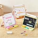 Three 3-in-1 Adjustable Tabletop Art Easels are arranged on a rug, each featuring a white surface with paper, a whiteboard, or a chalkboard with colorful artwork.