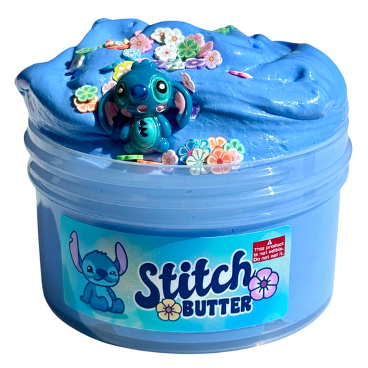 Stitch Butter is a blue butter slime with a blue Stitch charm, colorful flower decorations, and a blue Hawaiian scent. The jar features an illustrated Stitch character on the label.