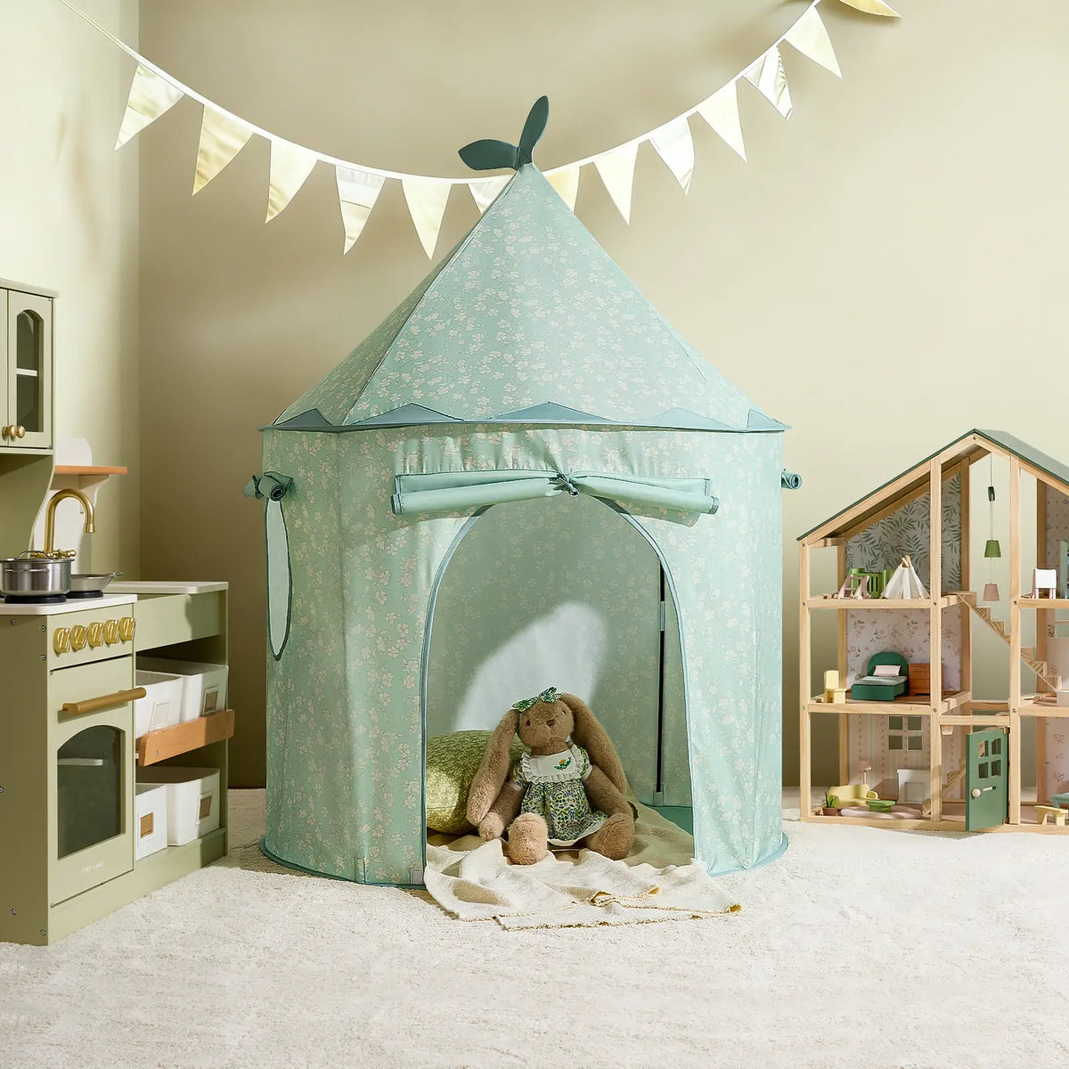 A floral print Starry Indoor Play Tent for Toddlers stands in a room beside a toy kitchen and a wooden dollhouse.