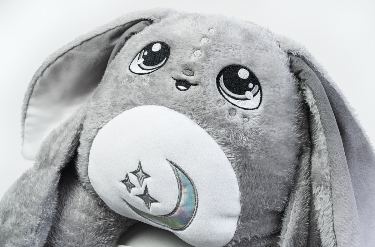 Gamma the Moon Pal – 5 lb Weighted Plush is a jumbo grey rabbit with large, embroidered eyes and a white belly patch featuring an embroidered crescent moon and stars, serving as a calming hug pillow.