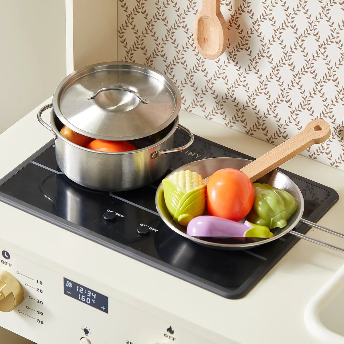PopJoy Play Kitchen with Lights & Sounds stove featuring a metal pot and a pan filled with plastic vegetables for pretend cooking.