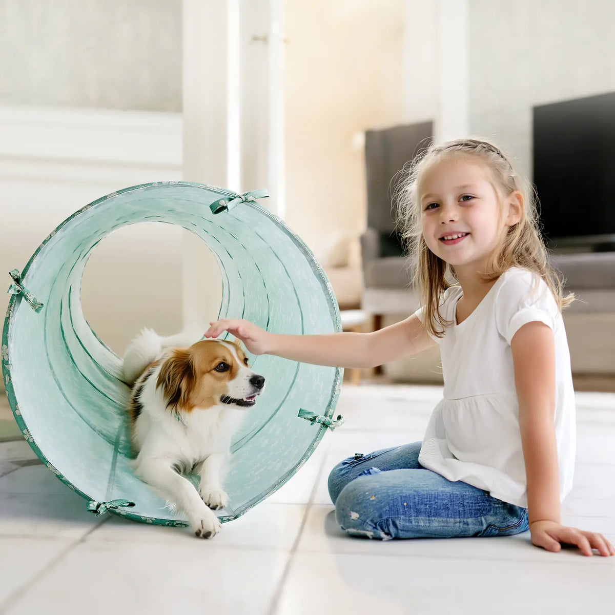 A young girl sits on the floor petting a small dog resting inside an Adventure Crawl Tunnel (68″).