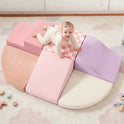 A baby crawls on a PlayNest Soft Foam Climbing Blocks – Violet set, which includes multi-colored ramps, steps, and semi-circular blocks arranged on a rug.