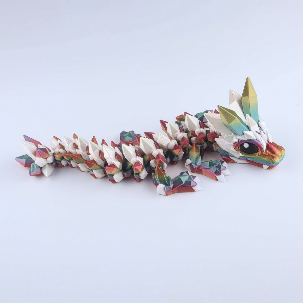 A Rainbow Silk Crystal Baby Dragon – Poseable Fidget Toy featuring an articulated, multi-colored design with pointed, crystalline scales on its back.