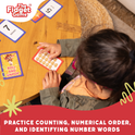 A child at a round wooden table uses a Counting & Numbers Card Pack to practice early math skills with number cards featuring illustrations of popping bubbles.