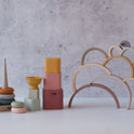 A 10-piece Silicone Rainbow Stacking Toy set including ring towers, nesting blocks, and silicone rainbow arches in muted earth tones.
