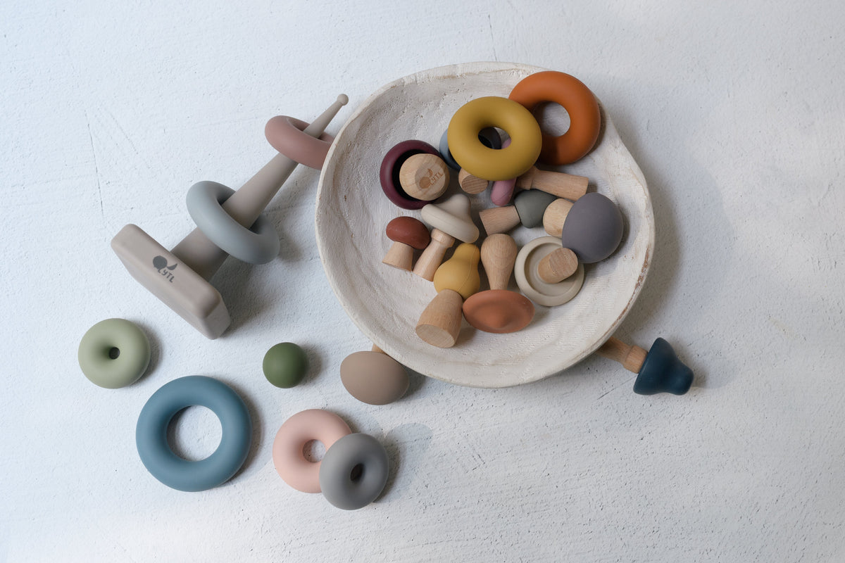 Montessori Fine Motor Play Bundle – 3 Toys featuring silicone and wooden stacking rings, mushroom-shaped pieces, and a stacking post arranged in a shallow bowl.