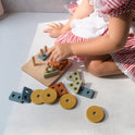 A child sits on the floor playing with the three wooden shape-sorting puzzles included in the Montessori Fine Motor Play Bundle – 3 Toys.