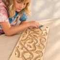 A child places a marble onto The Oort Cloud – Wooden Marble Run Puzzle, which features interlocking tracks.