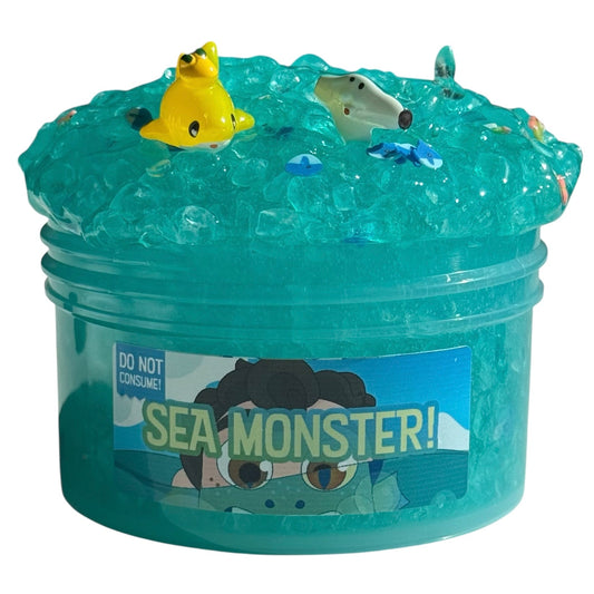 Sea Monster Teal Silica Slime (7 oz) features rainbow sherbet scent, a random fish charm, and comes in a clear container with "SEA MONSTER! DO NOT CONSUME!" label—perfect for sensory play and collecting.