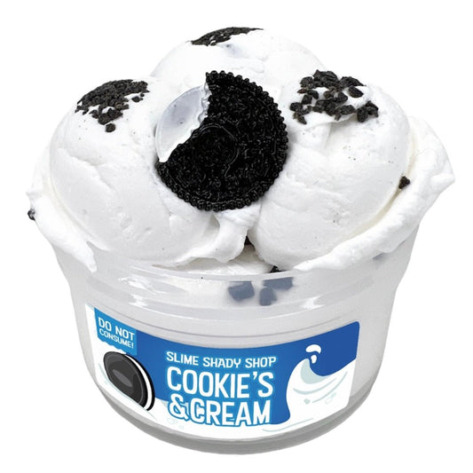A white cup labeled “Cookies n Cream” holds three scoops of cloud cream slime, topped with crushed chocolate cookie pieces, a half cookie, and a cute cookie charm. A DO NOT CONSUME warning appears on the label.