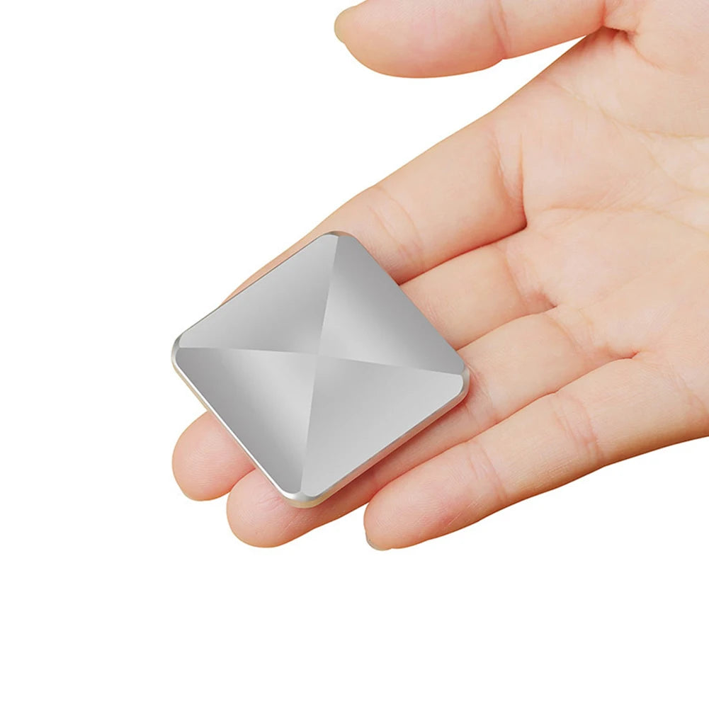 A hand holds a VKTECH Plastic Desk Toy Kinetic Skill Desktop Flip Rotating Fidget Spinner from Mainland China, featuring a metallic finish over durable plastic with a raised, pyramid-like surface and rounded corners.