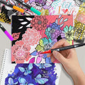 A hand showcases a Vibrant Dual Tip Brush Pen Marker over floral and butterfly art in pink, purple, blue, and yellow. The backdrop displays let love and wild and free, highlighting the pens artistic versatility.