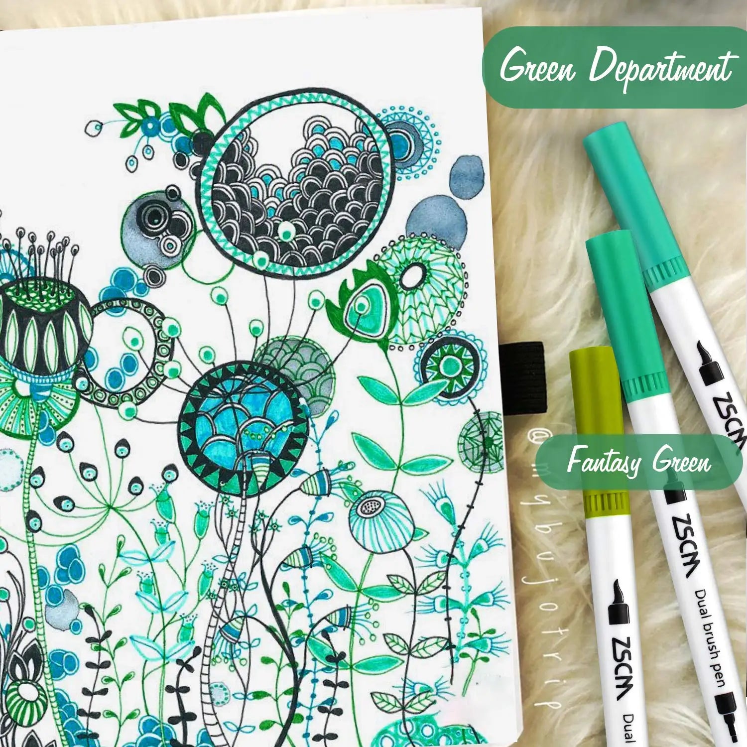 A page of intricate green and blue floral doodles with abstract patterns lies beside a Vibrant Dual Tip Brush Pen Marker Set. Nearby, three dual-tip pens in various shades of green are labeled Green Department and Fantasy Green.
