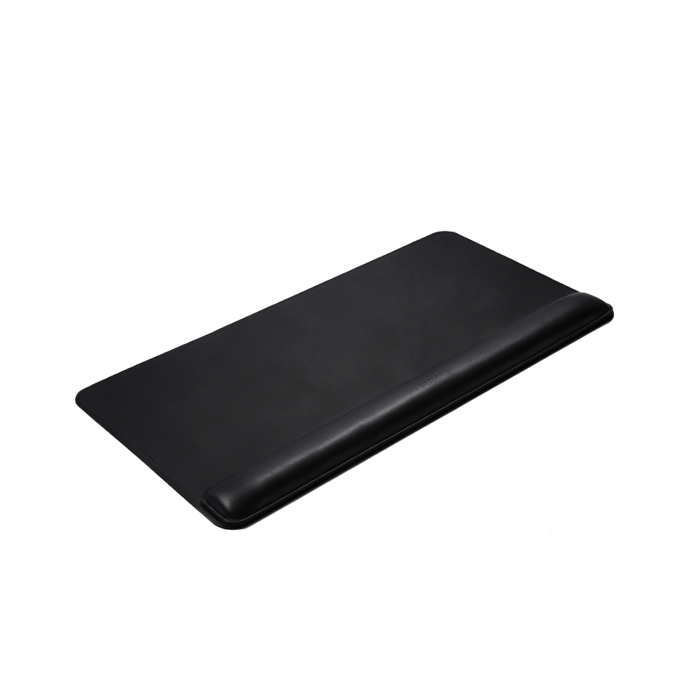 The Desk Mat Bundle is a rectangular black mat made from vegan leather with a built-in ergonomic wrist cushion, pictured on a white background.