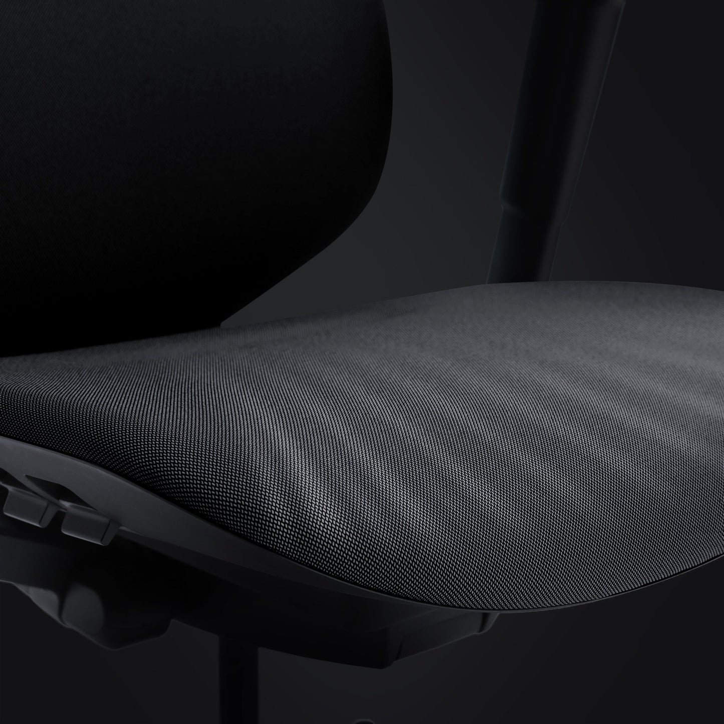 Close-up of the Hexcal Inspire Chair, a modern ergonomic seat featuring a dark mesh seat and black backrest, shown against a dark background. The luxury design and adjustment controls of the chair are partially visible.