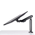 A Single Monitor Arm supports a computer monitor at a low, angled tilt above a white desk, displaying the side view of both the monitor and mounting arm for an ergonomic workspace.